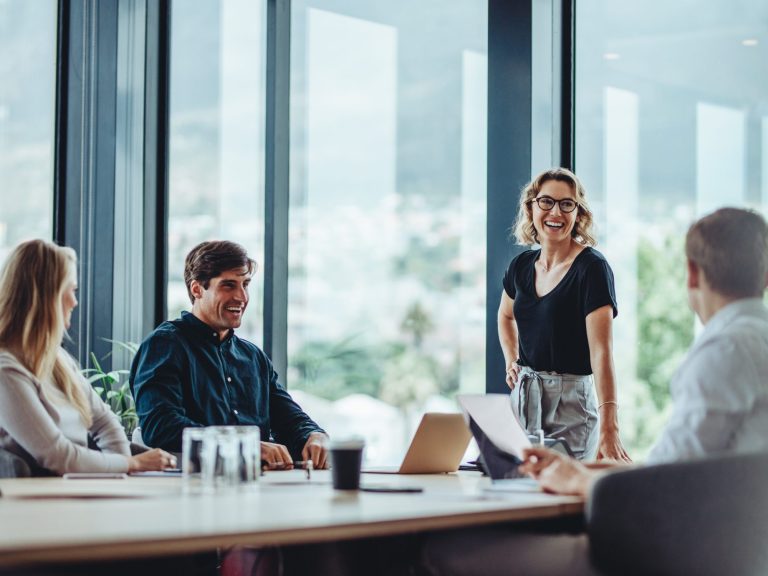 Smiling woman standing at table leading a meeting