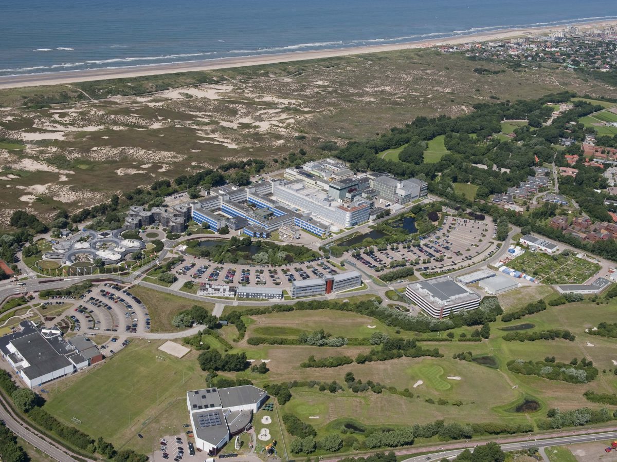 Photo of ESA's ESTEC campus in Netherlands from the south, showing buildings with the dunes and sea beyond