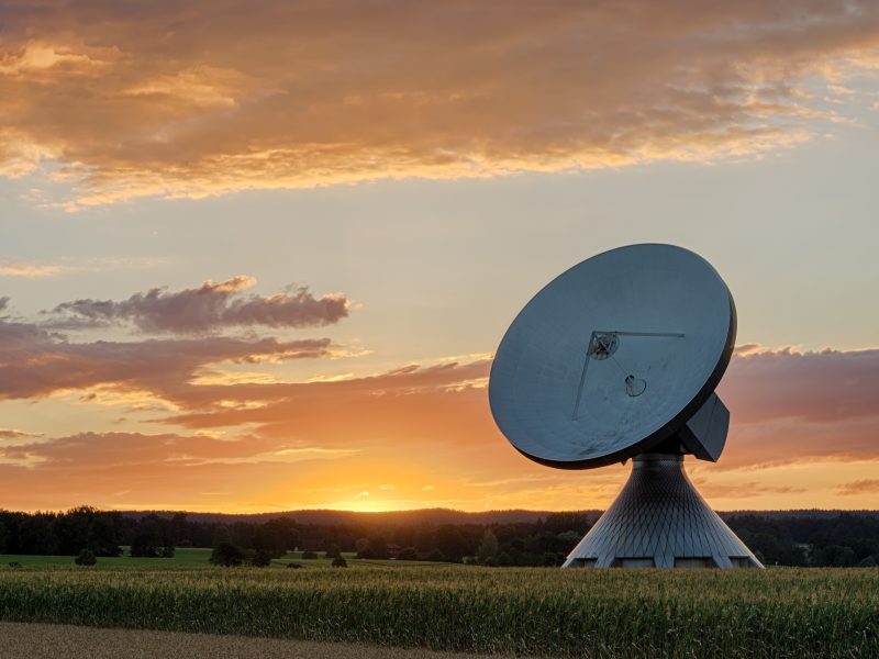satellite ground station dish against an orange sunset sky
